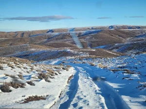 Camino cubierto de nieve atravesando las colinas del campo en venta en Chubut, Patagonia.