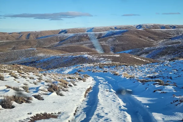 Camino cubierto de nieve atravesando las colinas del campo en venta en Chubut, Patagonia.