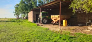 Tractor y equipo de trabajo guardados en galpón de finca rural en Buenos Aires.